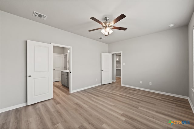 unfurnished bedroom featuring ensuite bathroom, light wood-type flooring, and ceiling fan