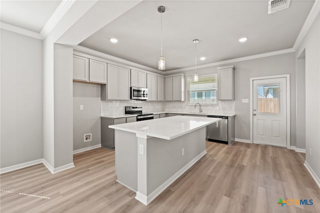 kitchen with ornamental molding, light wood-type flooring, appliances with stainless steel finishes, and a center island