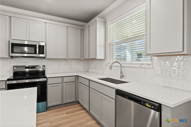 kitchen with gray cabinets, appliances with stainless steel finishes, sink, and light wood-type flooring