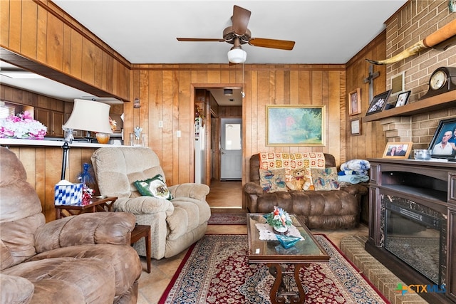 living room featuring a brick fireplace, wood walls, and ceiling fan