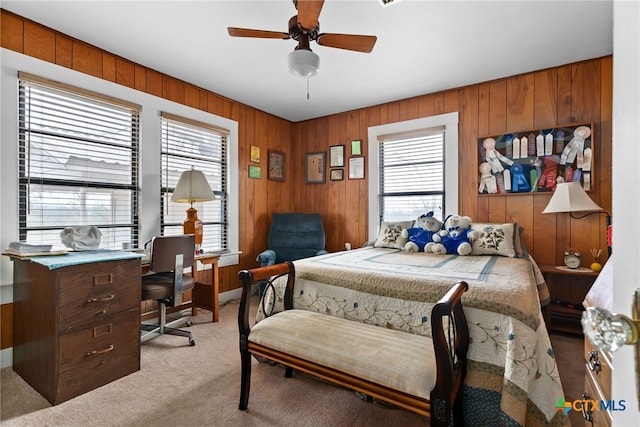 carpeted bedroom featuring ceiling fan and wooden walls