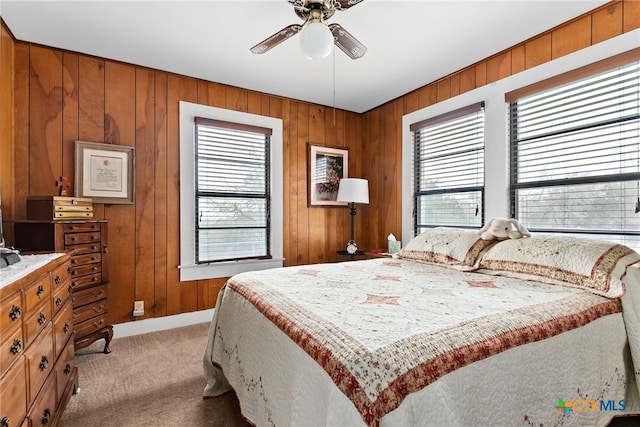 bedroom with ceiling fan, light colored carpet, and wooden walls