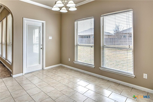 empty room with a healthy amount of sunlight, a notable chandelier, baseboards, and crown molding