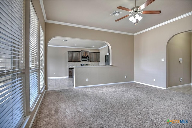 unfurnished living room featuring ornamental molding, arched walkways, light colored carpet, and baseboards