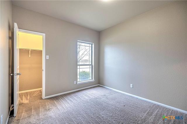 unfurnished bedroom featuring a walk in closet, light carpet, and a closet