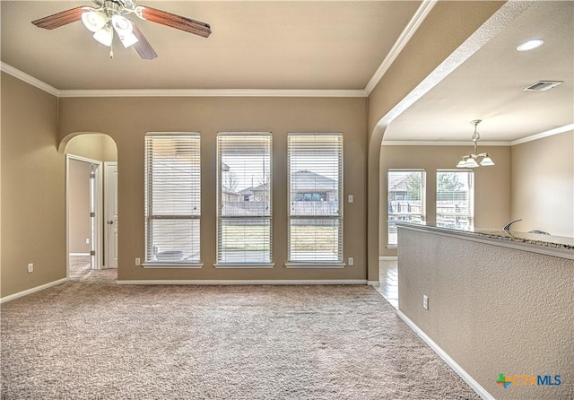 unfurnished room with ornamental molding, arched walkways, and carpet