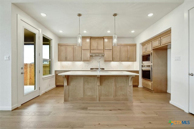 kitchen with hanging light fixtures, a kitchen island with sink, a healthy amount of sunlight, and stainless steel appliances