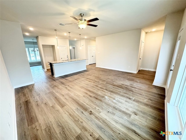 unfurnished living room with hardwood / wood-style floors, ceiling fan with notable chandelier, and sink