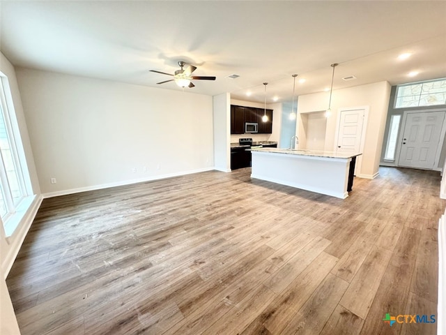 kitchen with sink, an island with sink, pendant lighting, ceiling fan, and hardwood / wood-style floors