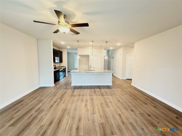 unfurnished living room featuring sink, wood-type flooring, and ceiling fan