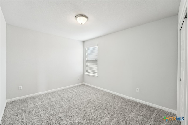 carpeted empty room featuring baseboards