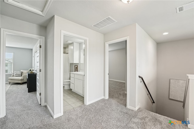 hallway featuring an upstairs landing, light colored carpet, baseboards, and attic access