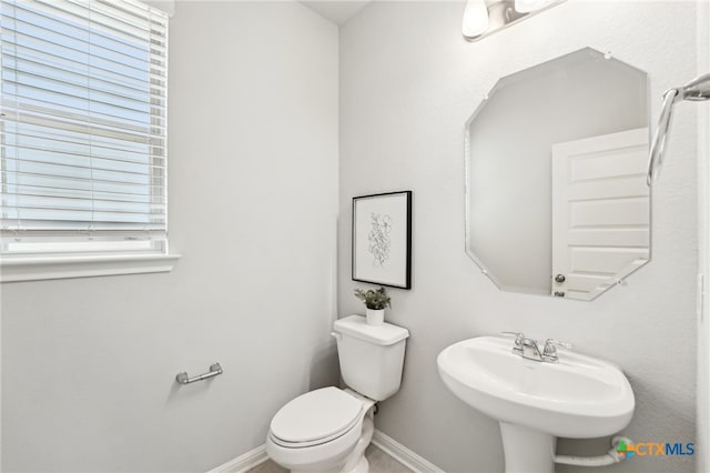 bathroom featuring a sink, baseboards, toilet, and plenty of natural light