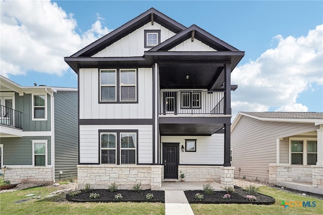 view of front of home featuring board and batten siding, a balcony, stone siding, and covered porch