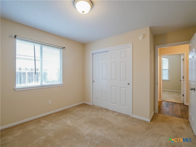 unfurnished bedroom with a closet and light colored carpet