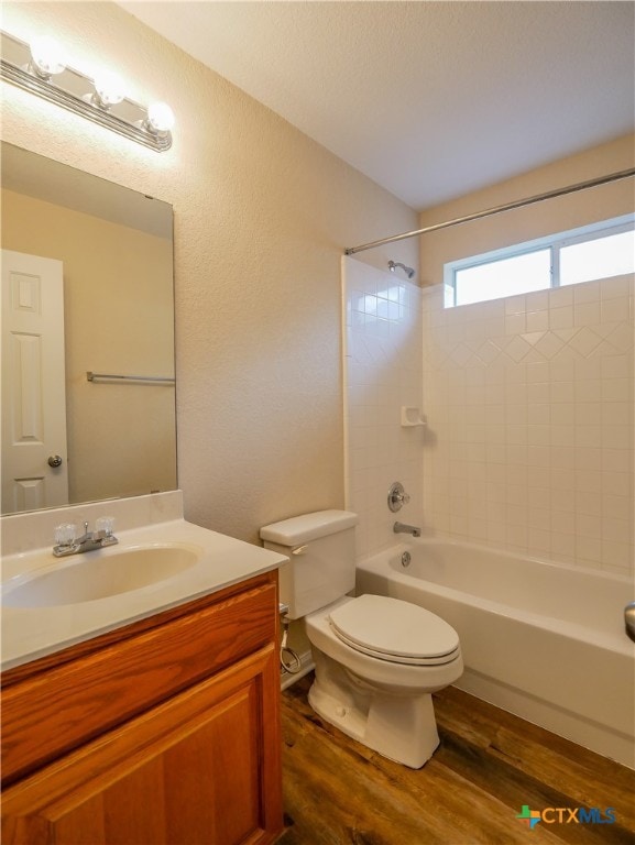 full bathroom with vanity, hardwood / wood-style floors, tiled shower / bath combo, and toilet