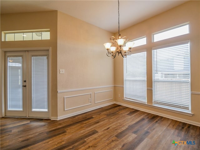 empty room featuring french doors, dark wood-type flooring, and an inviting chandelier