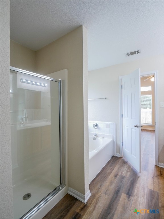 bathroom featuring separate shower and tub, wood-type flooring, and a textured ceiling