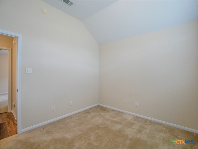 empty room with light colored carpet and vaulted ceiling