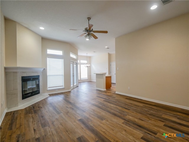 unfurnished living room with dark hardwood / wood-style floors, a fireplace, and ceiling fan with notable chandelier