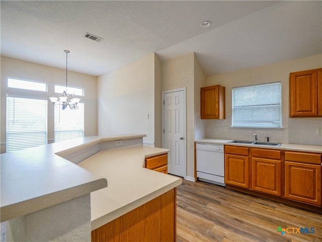 kitchen featuring decorative backsplash, light wood-type flooring, white dishwasher, pendant lighting, and a notable chandelier