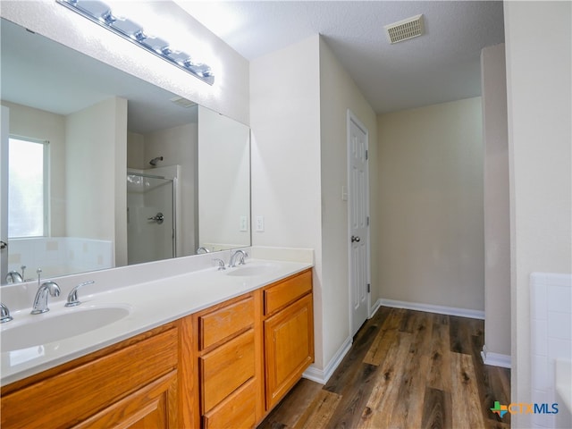 bathroom with separate shower and tub, vanity, wood-type flooring, and a textured ceiling