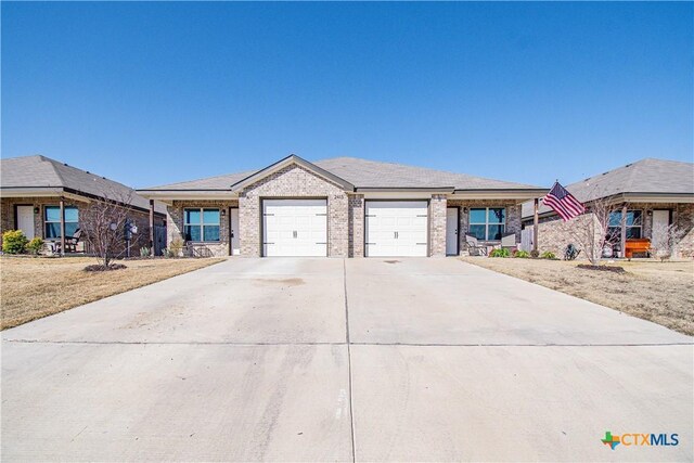 view of front of house featuring an attached garage, roof mounted solar panels, concrete driveway, and brick siding