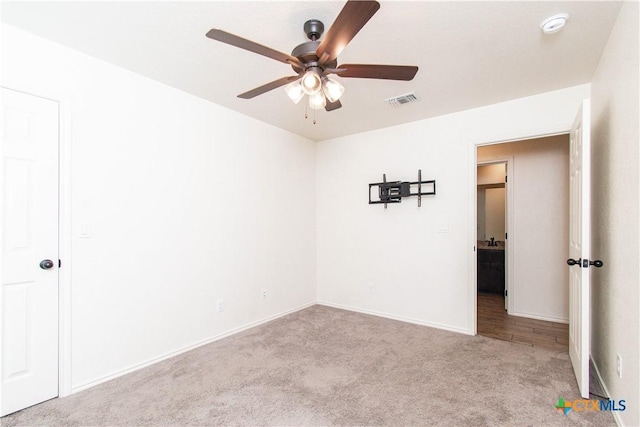 unfurnished room with light carpet, baseboards, visible vents, and a ceiling fan