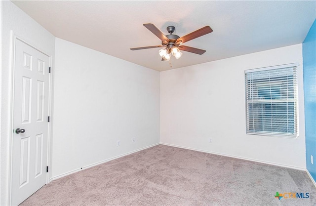 empty room featuring light colored carpet, ceiling fan, and baseboards