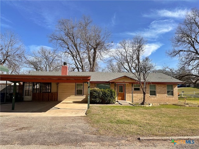 ranch-style home with a chimney, driveway, a front lawn, a carport, and brick siding