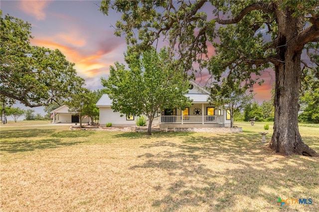 1600 Cattlemens Row, Lockhart, TX 78644 - back of house at dusk with covered porch, a lawn, and metal roof