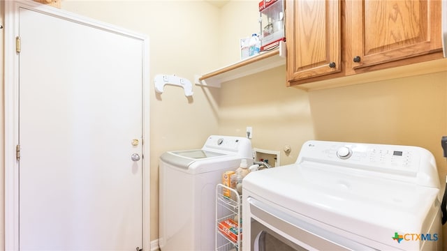 laundry area featuring washer and clothes dryer and cabinets