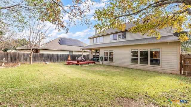 back of property with a lawn and a wooden deck