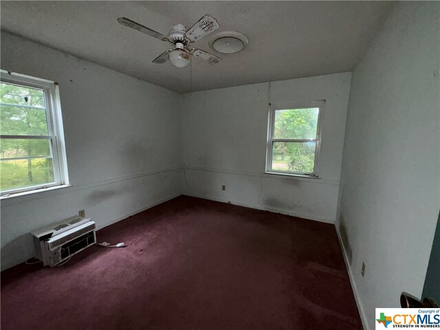 carpeted empty room featuring a wall mounted air conditioner and ceiling fan