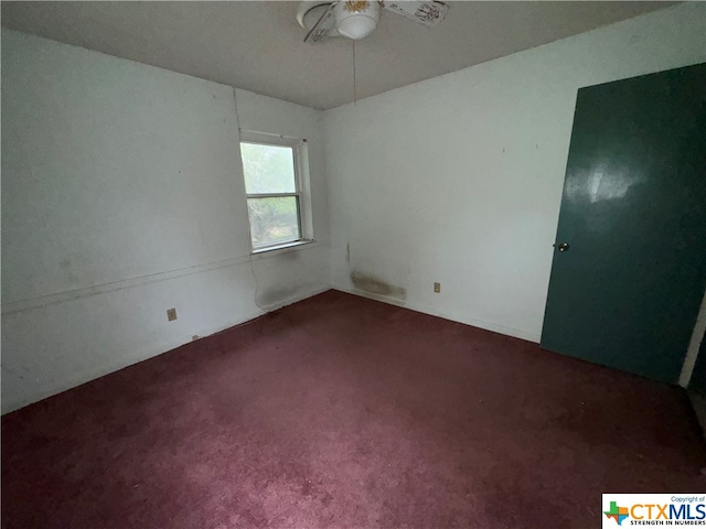 empty room with ceiling fan and dark carpet