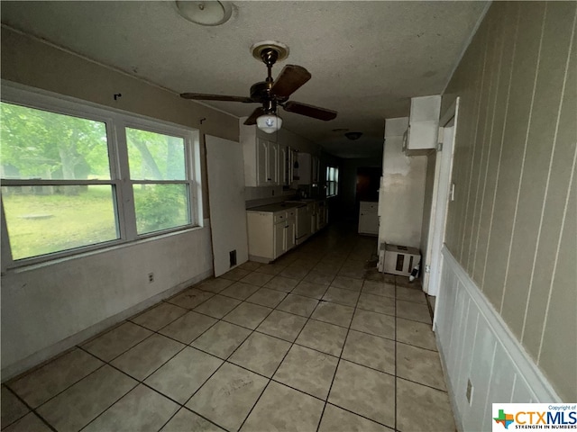 kitchen with ceiling fan, white cabinetry, and light tile patterned floors