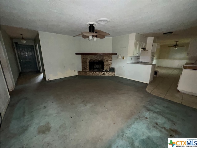 unfurnished living room featuring concrete floors, a textured ceiling, and a brick fireplace