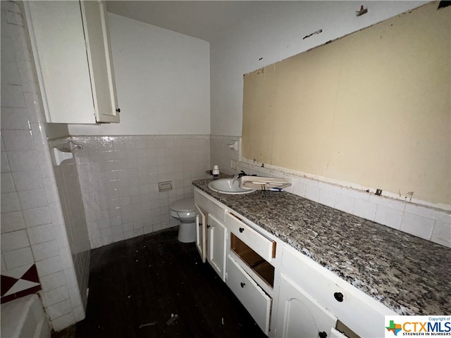 bathroom featuring vanity, tile walls, and toilet