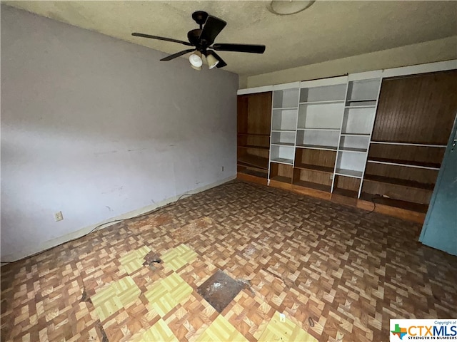 unfurnished room with dark parquet flooring and ceiling fan