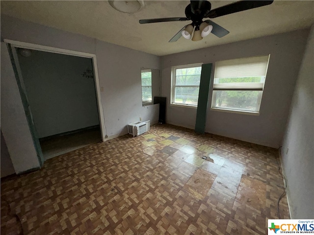 unfurnished room with a wall unit AC and ceiling fan