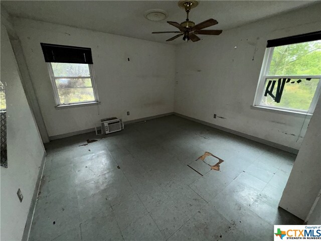 spare room featuring an AC wall unit, a wealth of natural light, and ceiling fan