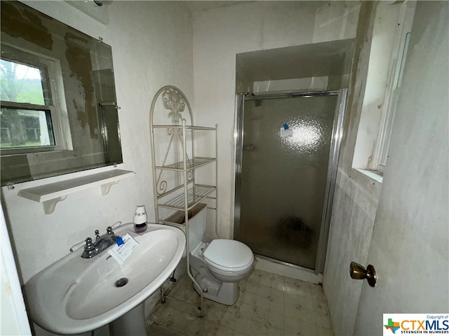 bathroom featuring toilet, a shower with door, and sink