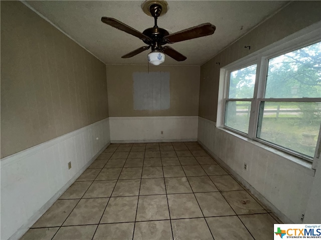 tiled spare room with ceiling fan