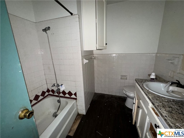 full bathroom featuring tiled shower / bath combo, toilet, tile walls, and vanity