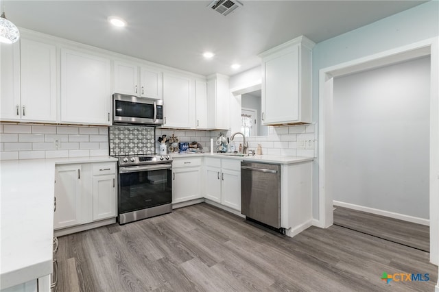 501 College Ave, Florence, TX 76527 - kitchen featuring appliances with stainless steel finishes, wood finished floors, light countertops, white cabinetry, and tasteful backsplash