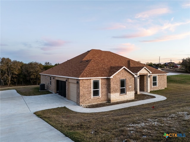 view of front of property with a yard, a garage, and central air condition unit