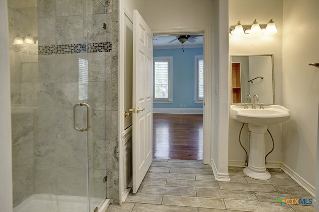 bathroom featuring ceiling fan, a shower with door, sink, and ornamental molding