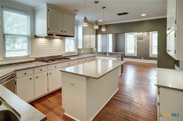 kitchen with crown molding, stainless steel appliances, hanging light fixtures, light hardwood / wood-style floors, and a center island