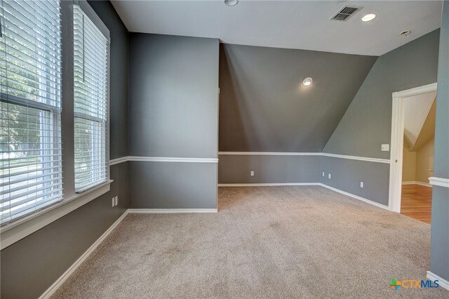 spare room with light carpet and vaulted ceiling