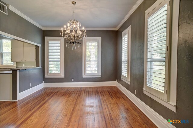 unfurnished dining area featuring a chandelier, crown molding, and light hardwood / wood-style flooring